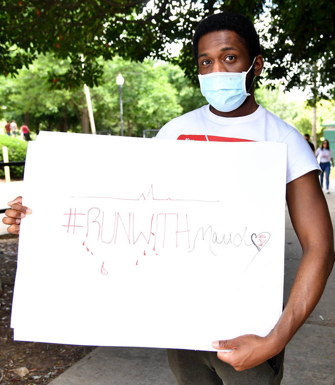 Social media personality Ayoo Travv displays a sign that reads "#RunWithMaud"