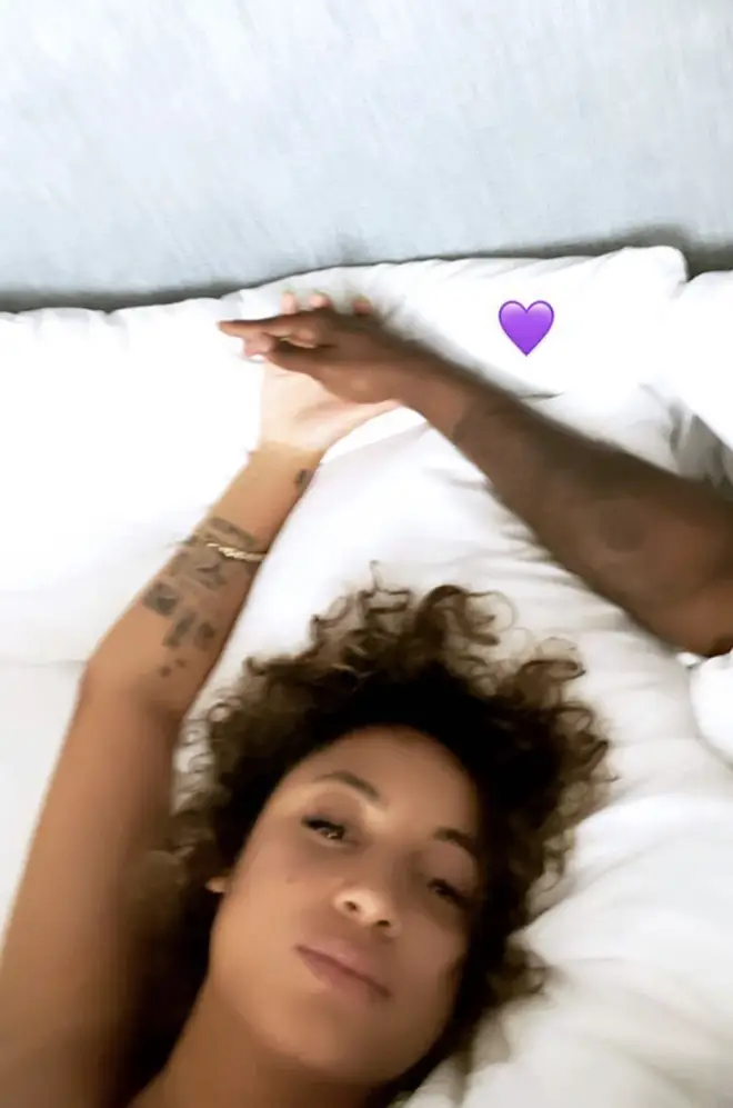 DaniLeigh shared a photo of herself in bed holding the hand of her mystery man, supposedly DaBaby.