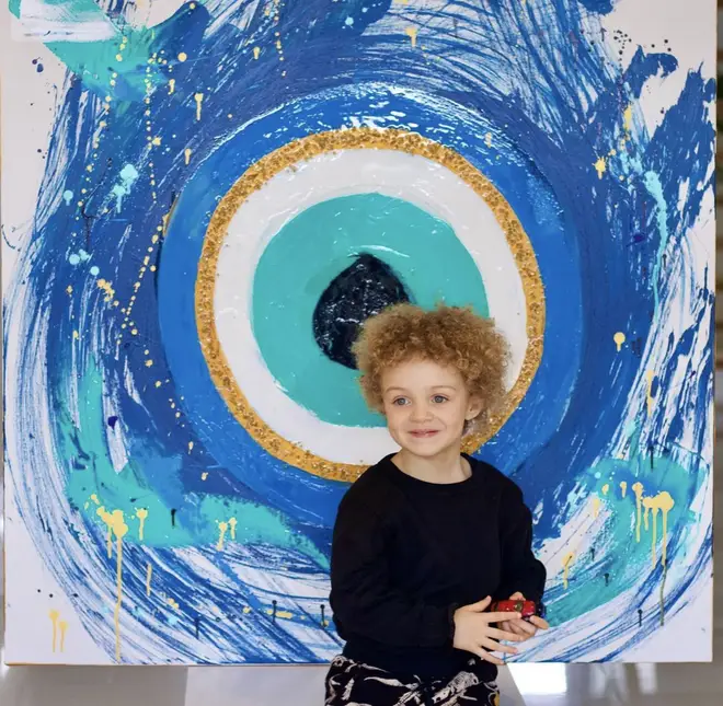 Adonis poses infant of a 'evil eye' painting made by his mother, Sophie Brussaux.