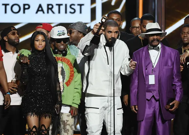 Rappers Nicki Minaj and Lil' Wayne look on as recording artist Drake accepts the Top Artist award onstage with his father Dennis Graham during the 2017 Billboard Music Awards.