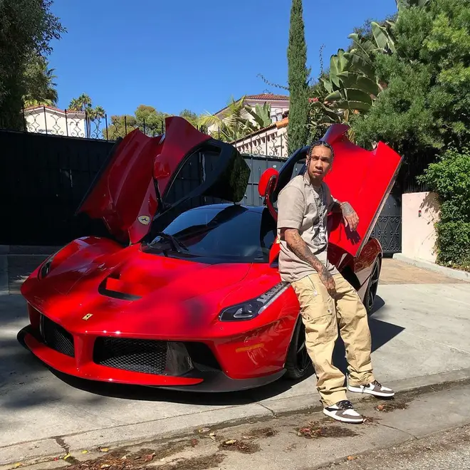 Tyga leans against his red Ferrari in the photo, spotting a pair of Travis Scott's Air Jordan 1's.